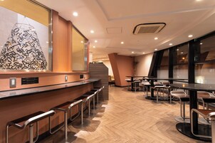 Un área de bar moderna con suelo de madera, taburetes de metal y una gran obra de arte abstracta en la pared.