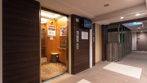 L’intérieur d’un ascenseur, avec un revêtement en bois, une poubelle et des affiches d’information.