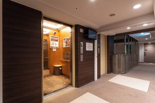 Interior de ascensor con detalles de madera, un cubo de basura y carteles informativos.