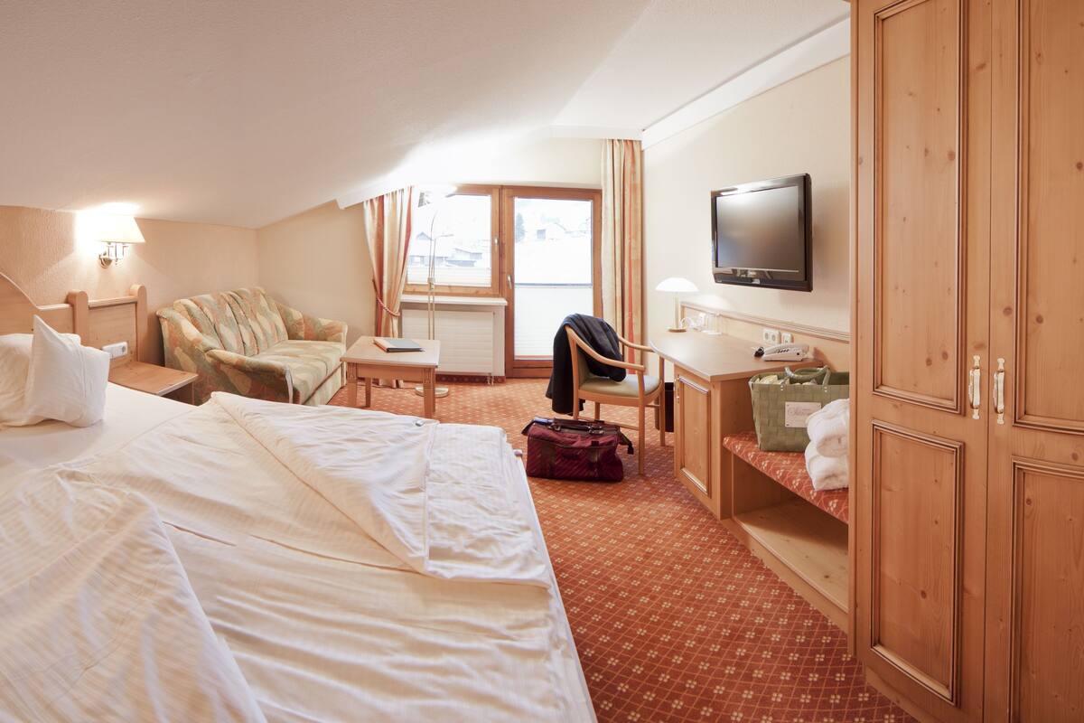 Ein Hotelzimmer mit einem Bett, einem Schlafsofa, einem Schreibtisch, einem Fernseher und einem Kleiderschrank.
