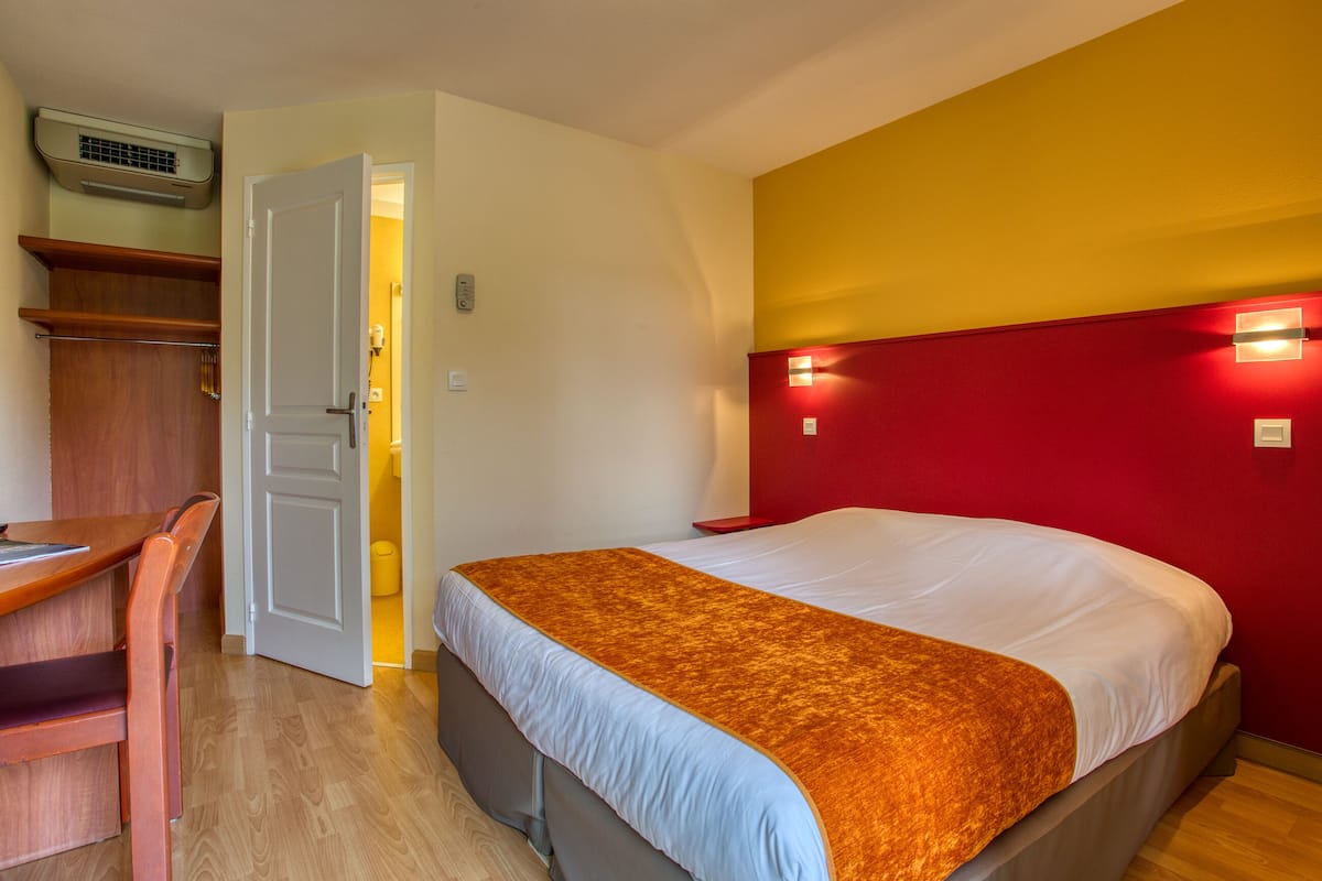 A hotel room with a bed, a desk, and a wardrobe.