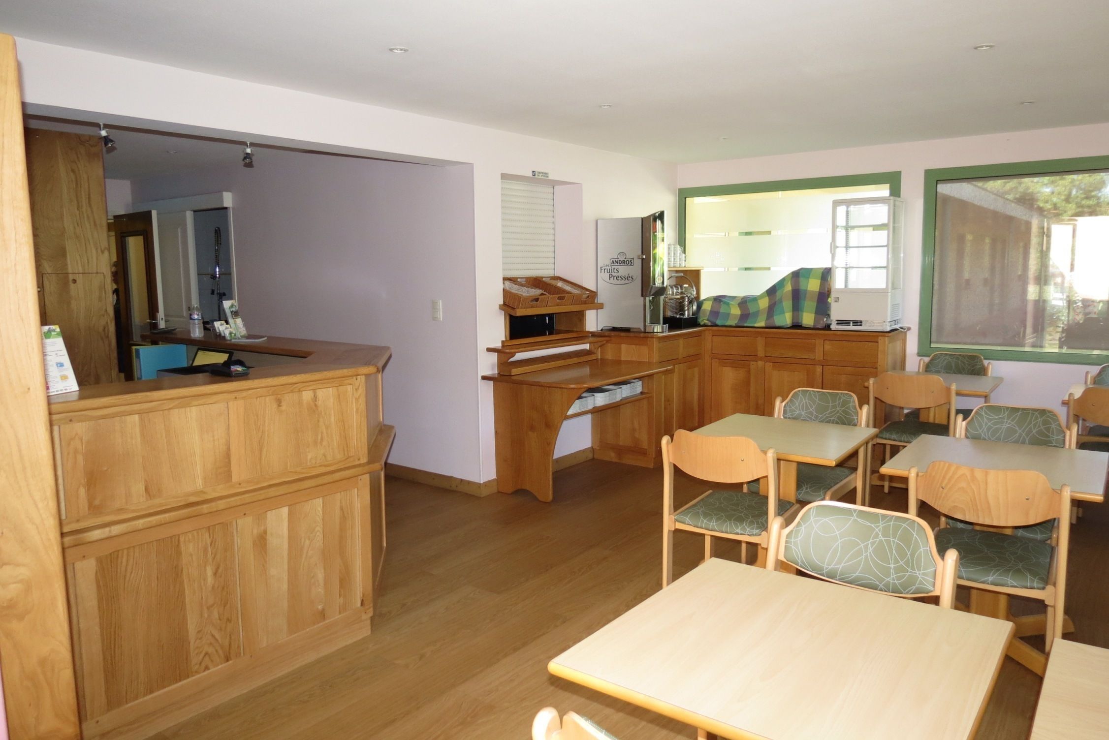 A room with wooden furniture, a kitchen area, and a window with a view.