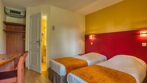 Una habitación con dos camas, un escritorio de madera y una pared de acento roja.