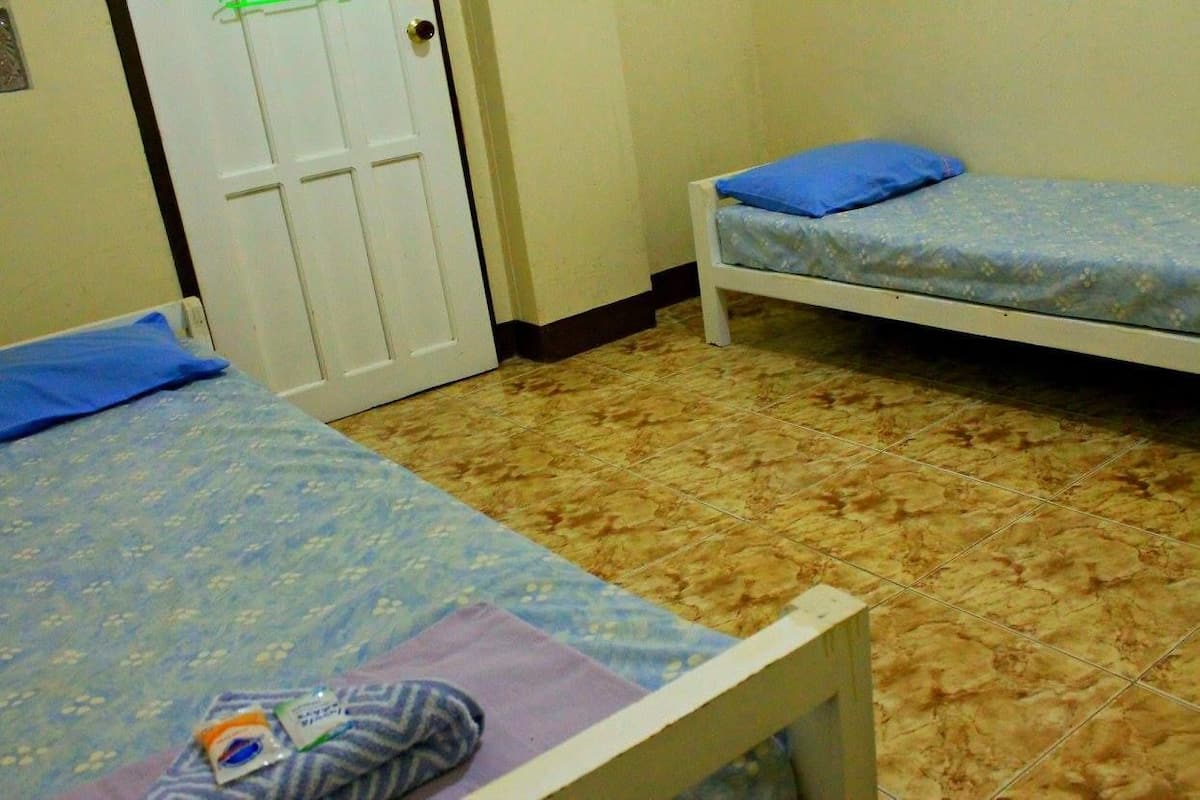 A room with two single beds, a door, and a tiled floor.