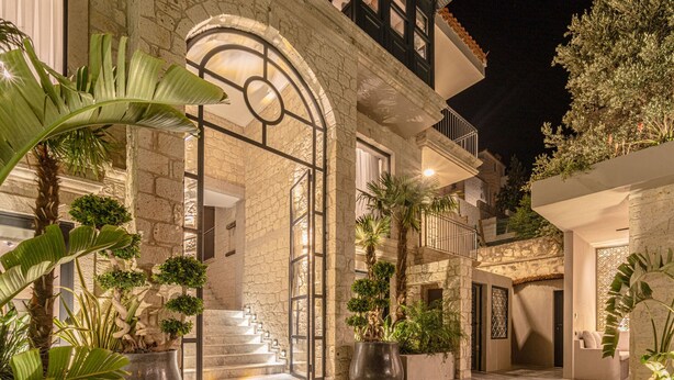 Un edificio in pietra con un'imponente entrata, una scalinata e piante in vaso.