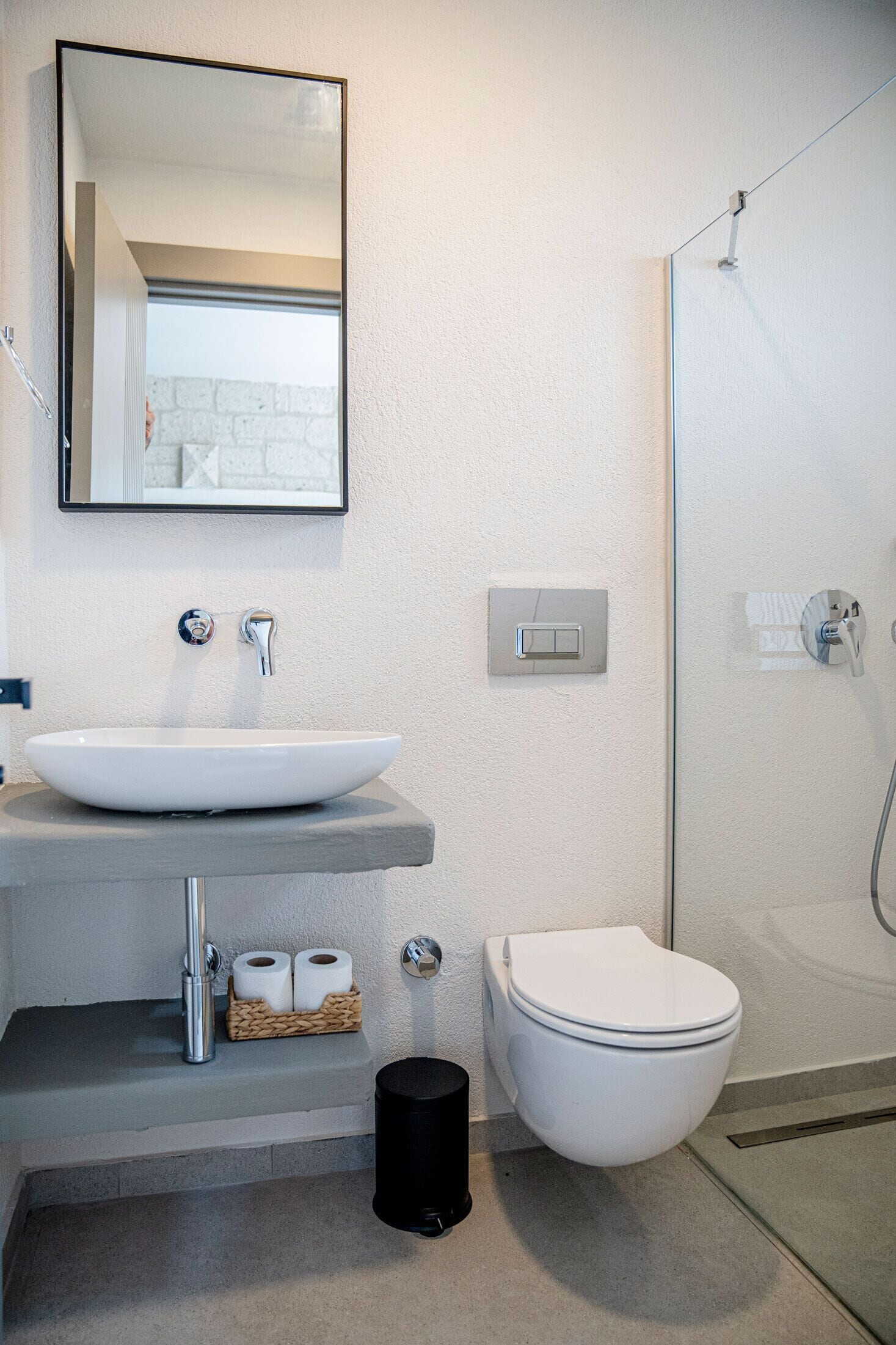 A bathroom with a white sink, a mirror, a toilet, and a shower.