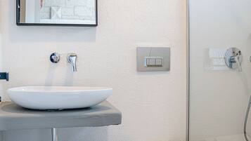 A bathroom with a white sink, a mirror, a toilet, and a shower.
