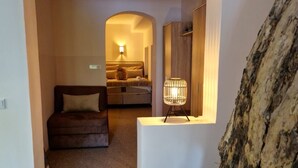 A modern interior with a staircase leading to a bedroom, a small table with a lamp, and a rock feature. - Pansion River (Sarajevo)