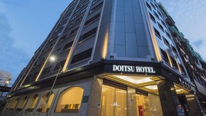 Un edificio de gran altura con el letrero "DOITSU HOTEL" en la fachada.
