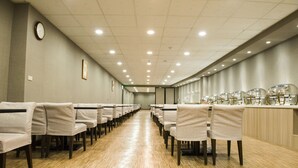 Un salón de conferencias con filas de sillas, un reloj en la pared y un mostrador con vasos.