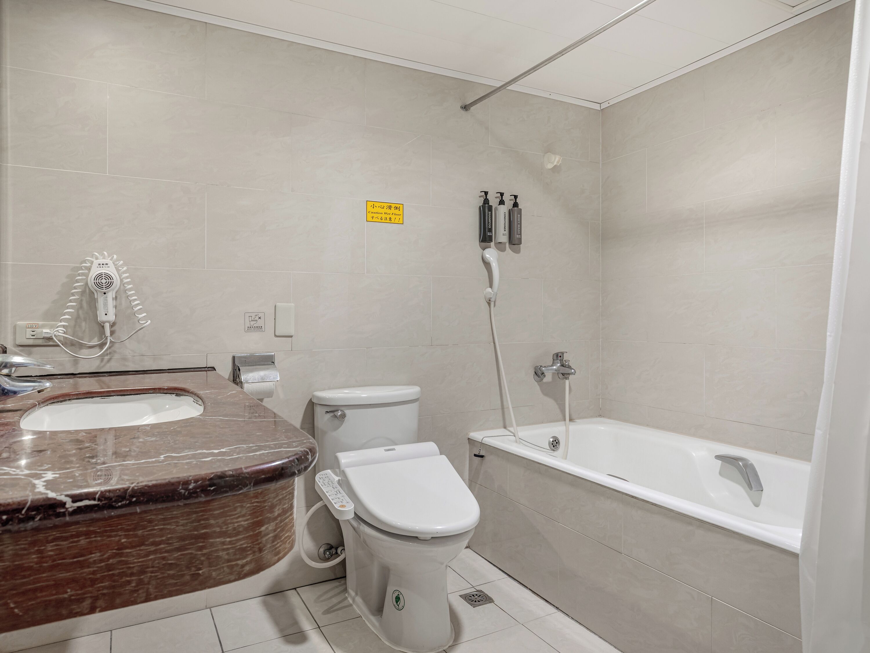 A bathroom with a toilet, bidet, and bathtub.