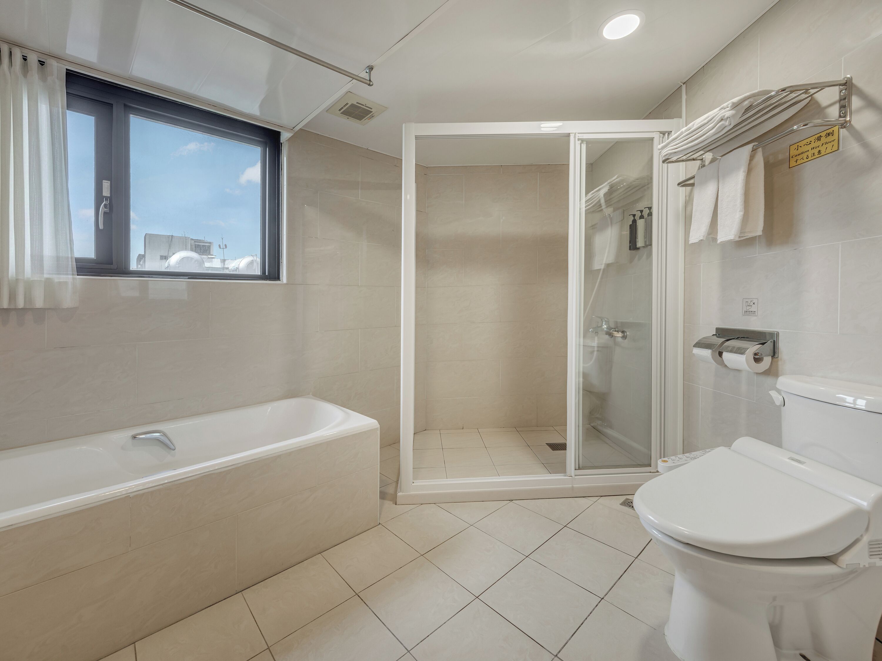 A modern bathroom with a bathtub, toilet, and glass-enclosed shower.