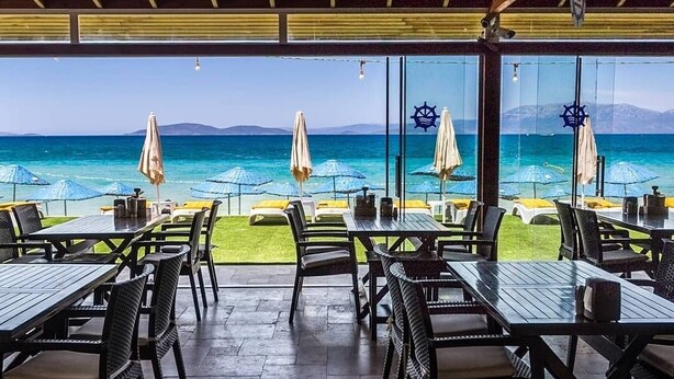 An outdoor dining area with tables and chairs, overlooking the sea. - Firat Mert Hotel (Cesme)