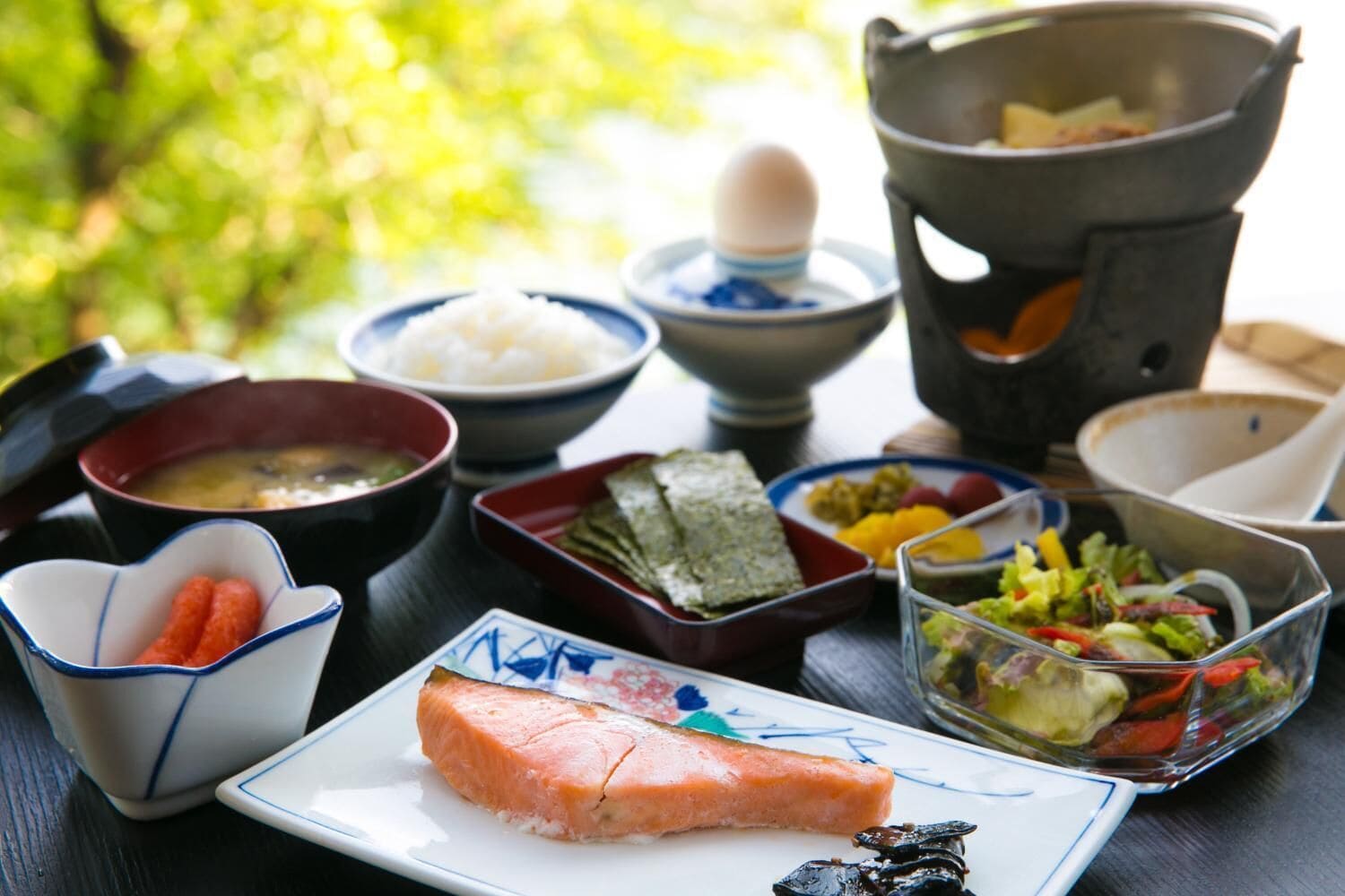 Una comida tradicional japonesa con diversos platos, incluyendo salmón, arroz y verduras.