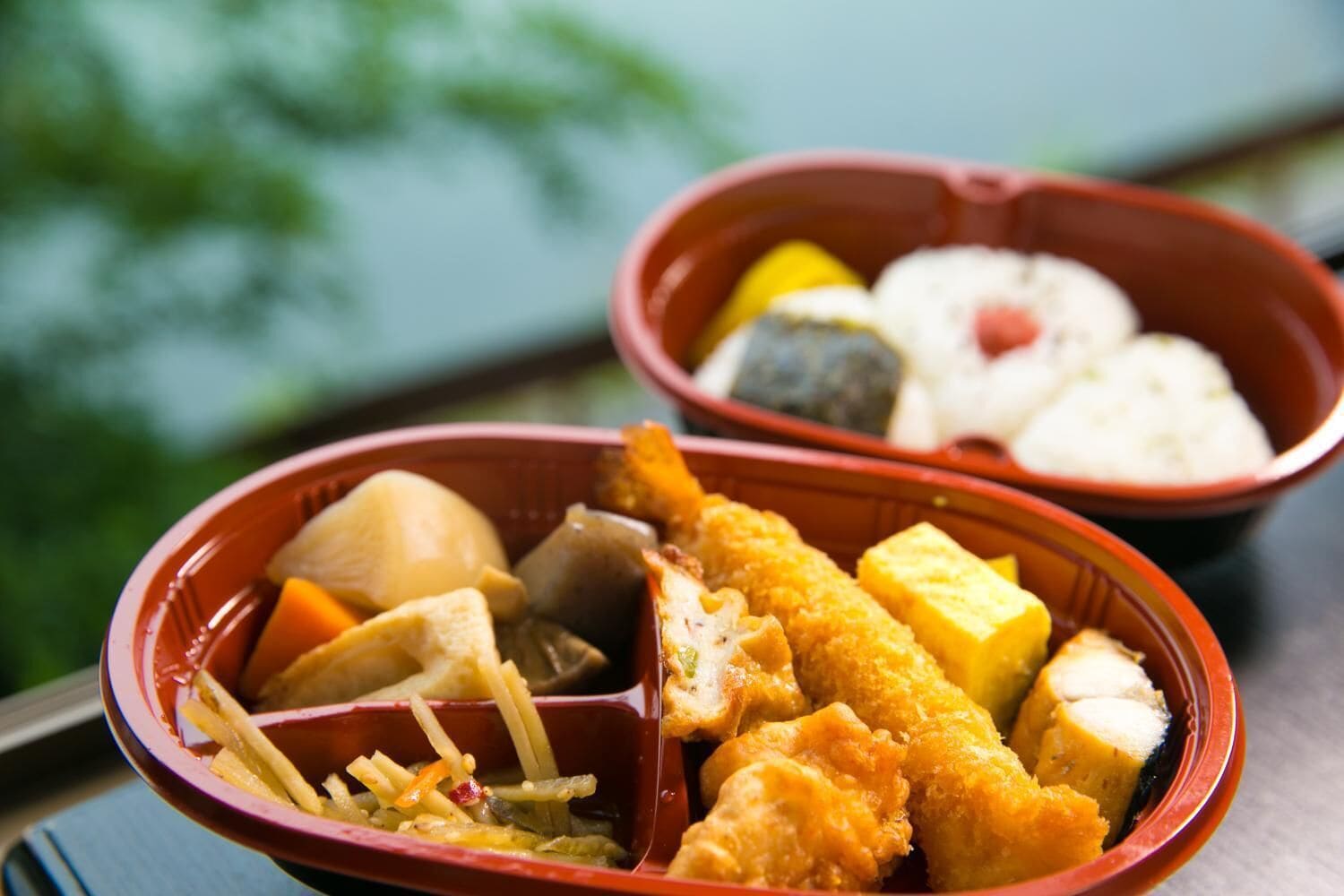 A meal with various dishes including fried items, tofu, and vegetables in a red bowl.