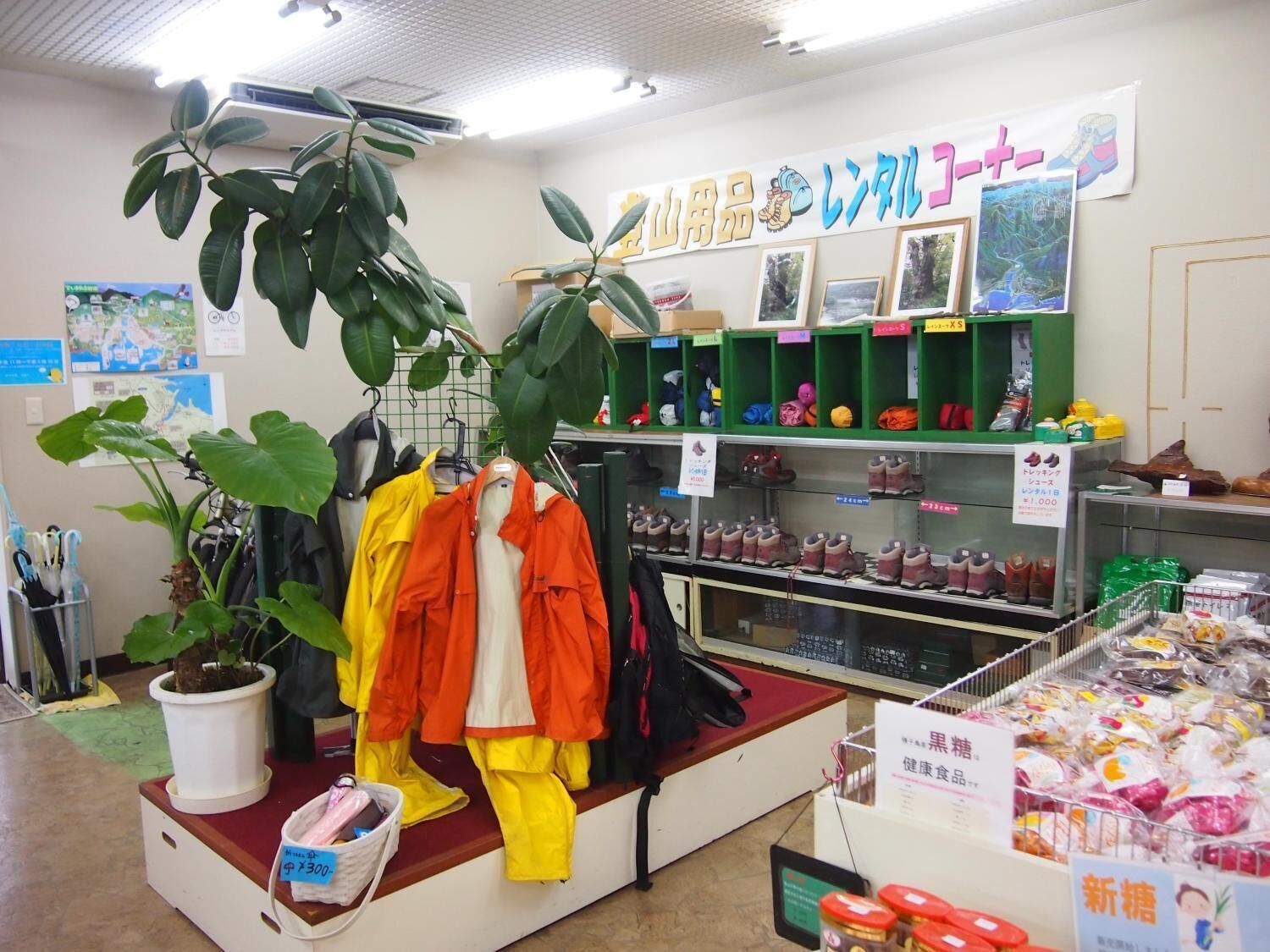 A retail store with clothing racks, shelves with shoes, and a display of packaged goods.