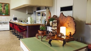 A modern kitchen with a bar area, a large wooden sculpture, and a green mat on the counter. - Tashiro Bekkan (Yakushima)
