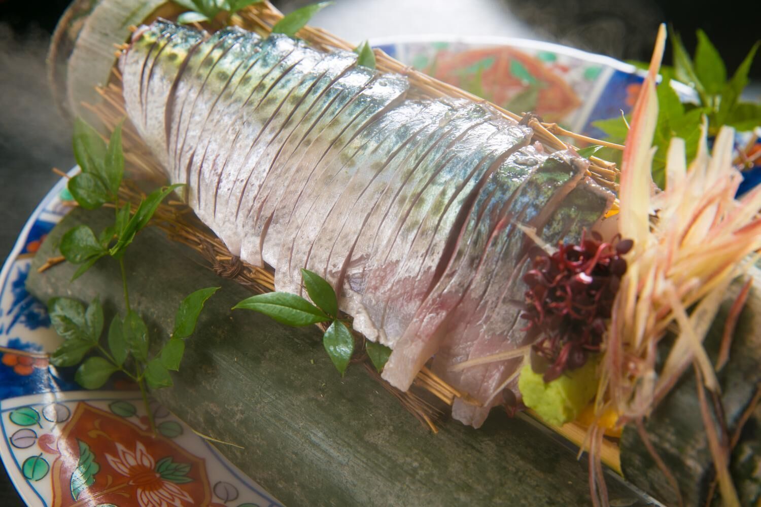 A whole fish on a decorative plate with leaves and flowers.
