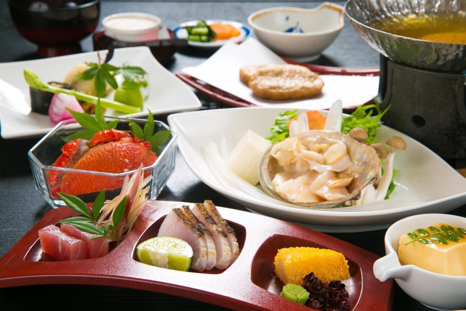 Diverse gerechten, waaronder sashimi, een kom soep en een bord met gele rijst.