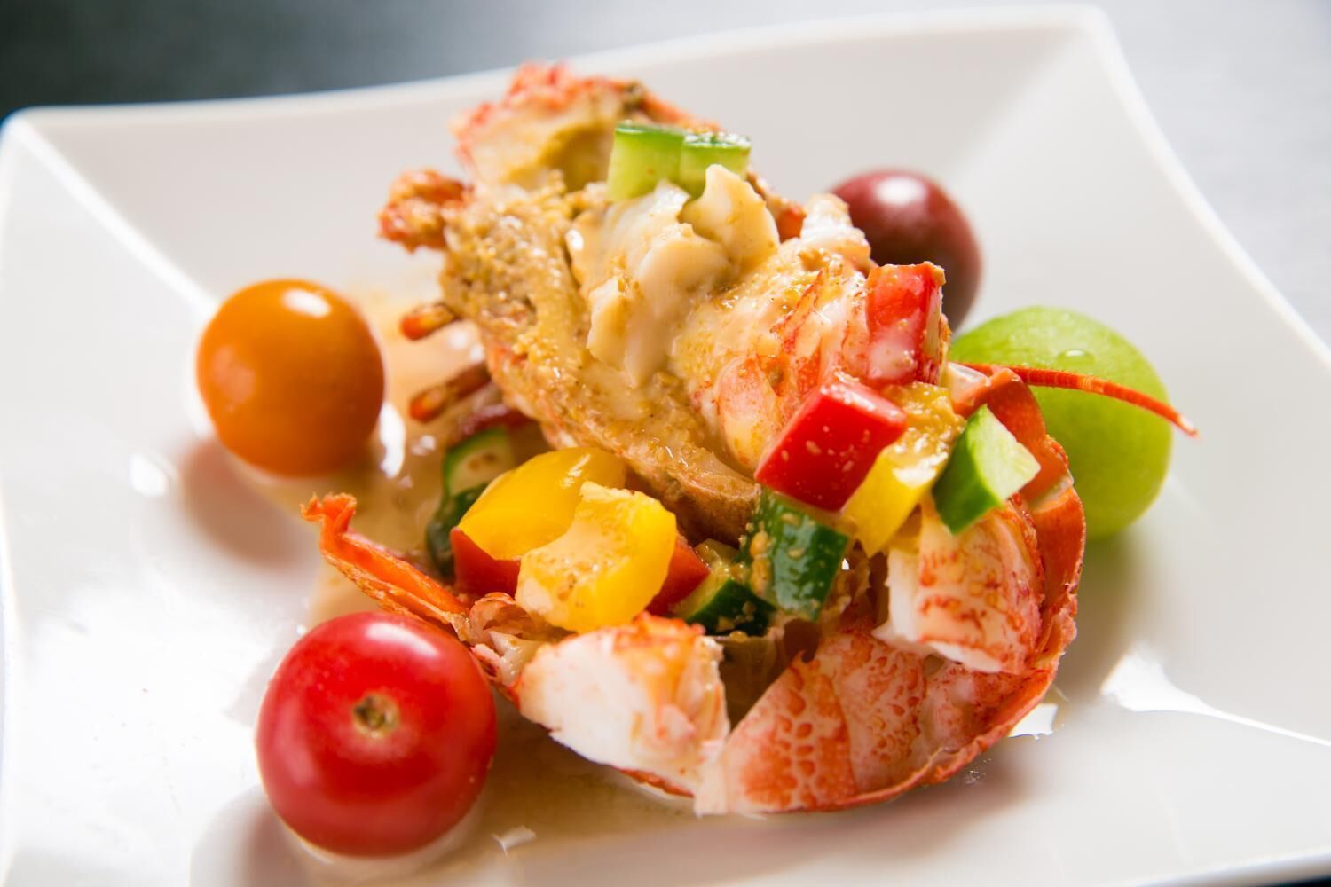 A lobster tail with vegetables on a white plate.