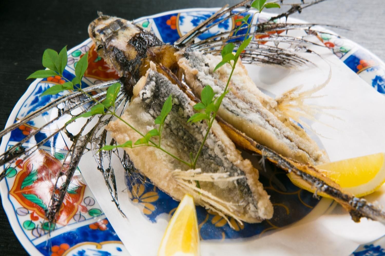 Une assiette avec deux poissons entiers, des quartiers de citron et quelques herbes.
