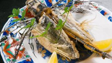 Une assiette avec deux poissons entiers, des quartiers de citron et quelques herbes.