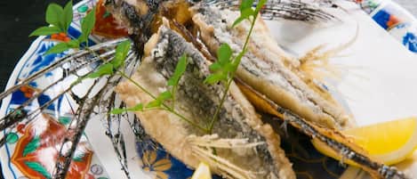 Un plato con dos pescados enteros, cuñas de limón y algunas hojas verdes.