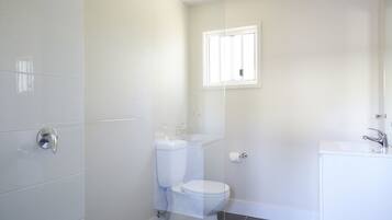 A bathroom with a toilet, sink, and shower area.