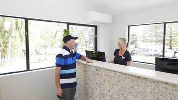 A reception area with a stone counter, large windows, and a view of parked vehicles outside.