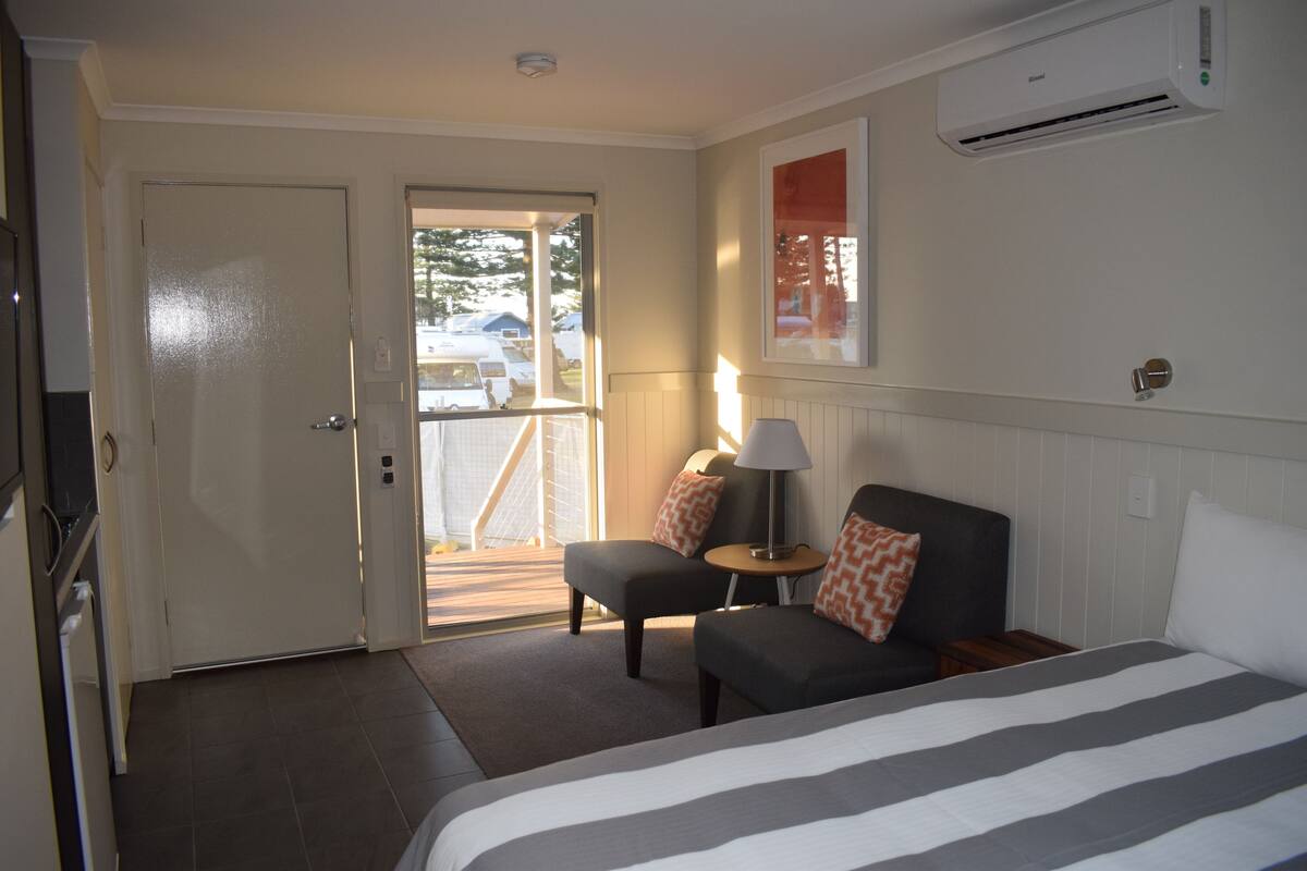 Une chambre d’hôtel avec un lit, un canapé, une petite table et une porte donnant sur un balcon.
