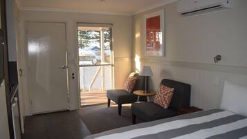 A hotel room with a bed, a sofa, a small table, and a door leading to a balcony.