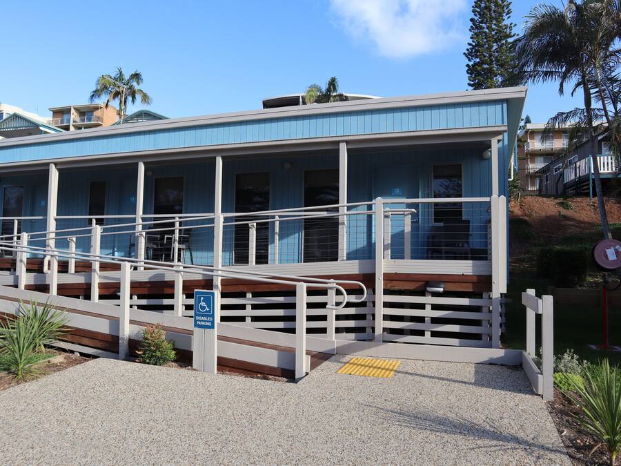 A building with a blue exterior, a ramp with a handrail, and a sign indicating disabled parking.