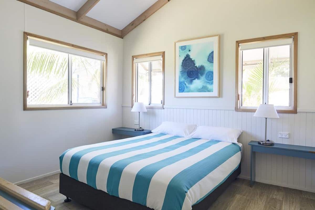 Une chambre à coucher avec un lit, deux tables de chevet, deux lampes et un tableau au mur.