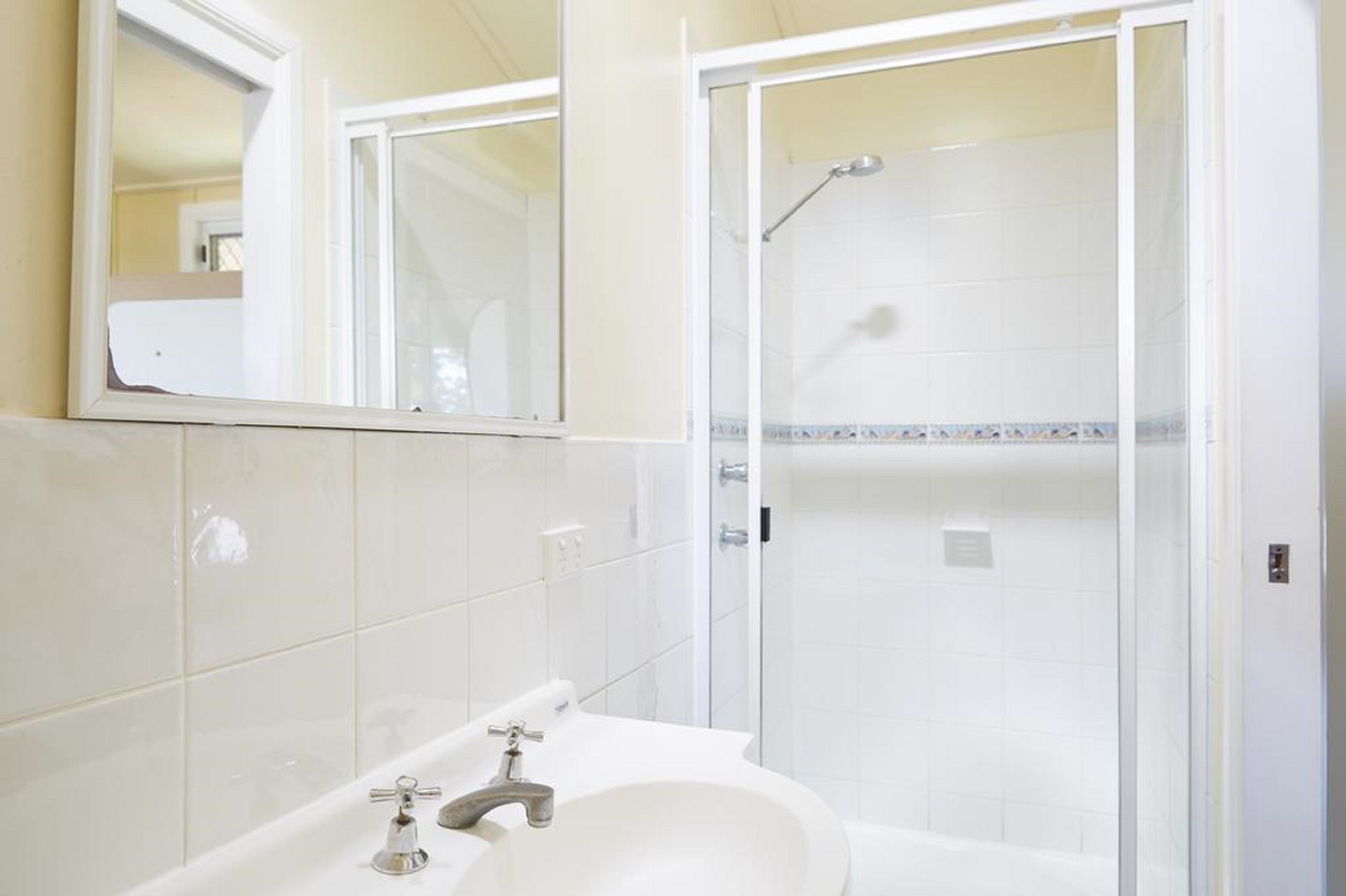 Une salle de bain avec un lavabo blanc, un miroir et une cabine de douche.