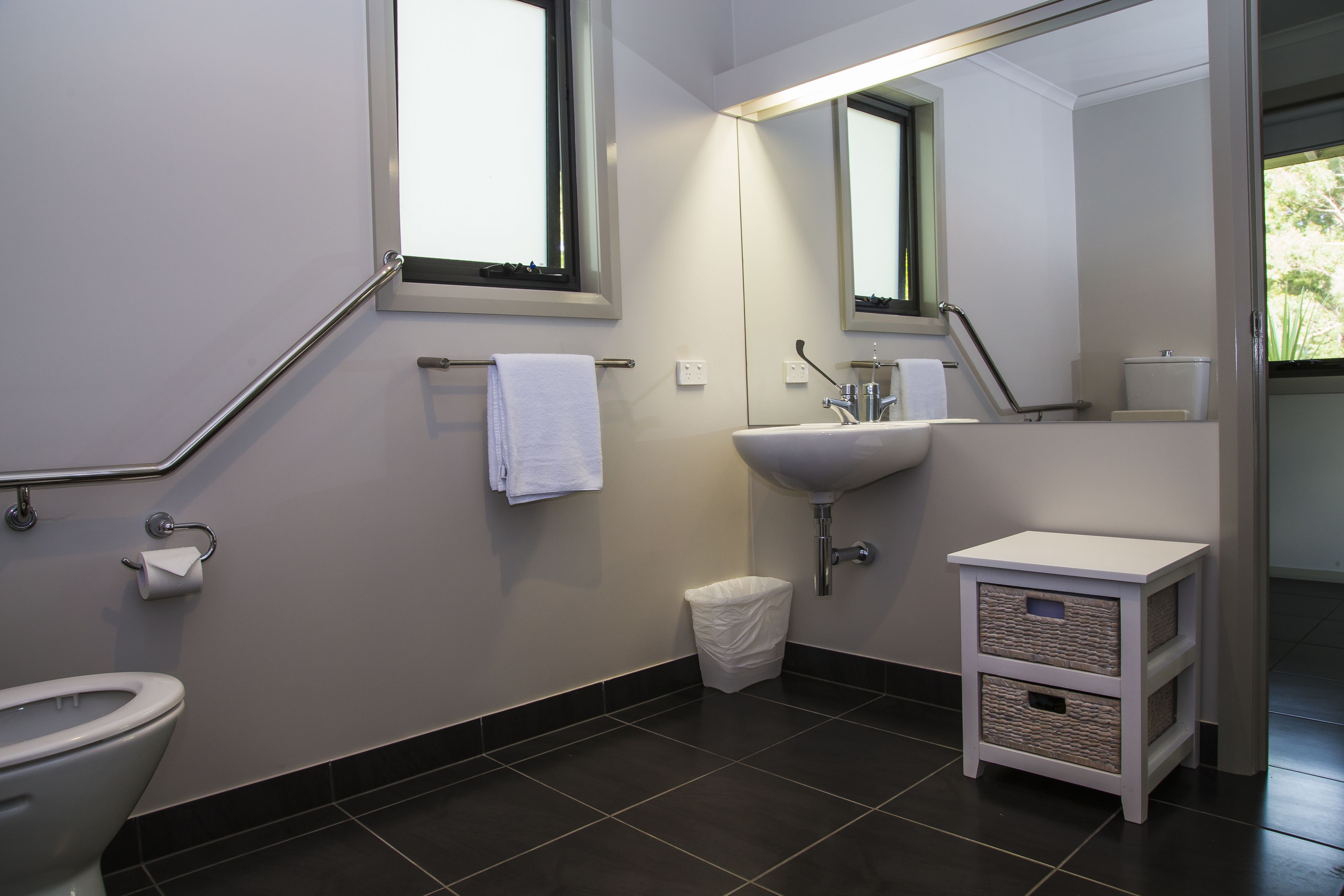 A modern bathroom with a toilet, sink, and a small cabinet.