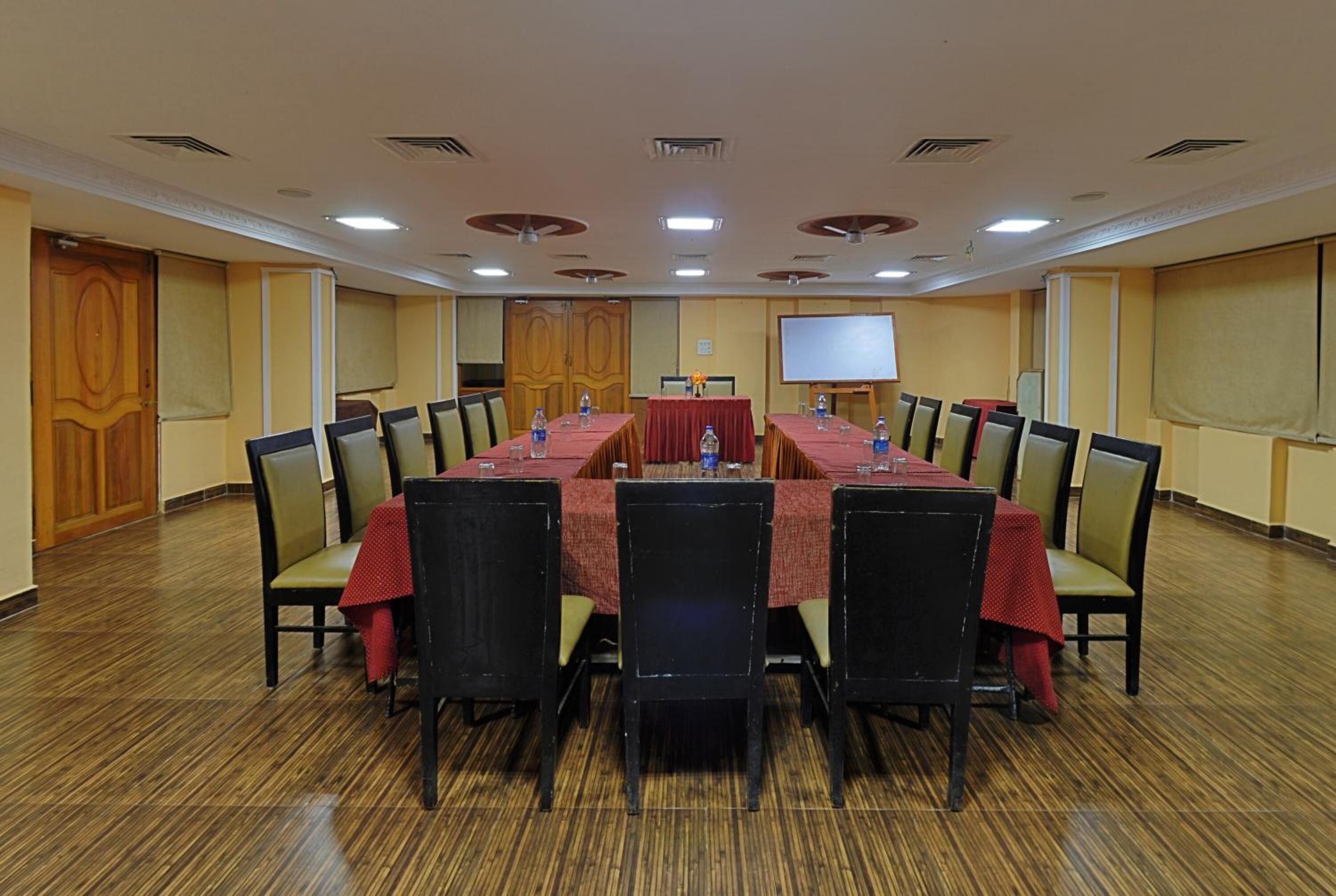 A conference room with a long table, chairs, a projector screen, and a whiteboard.