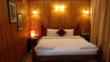 Una habitación con paneles de madera, una cama, dos lámparas fijadas a la pared y una mesita de noche con lámpara.