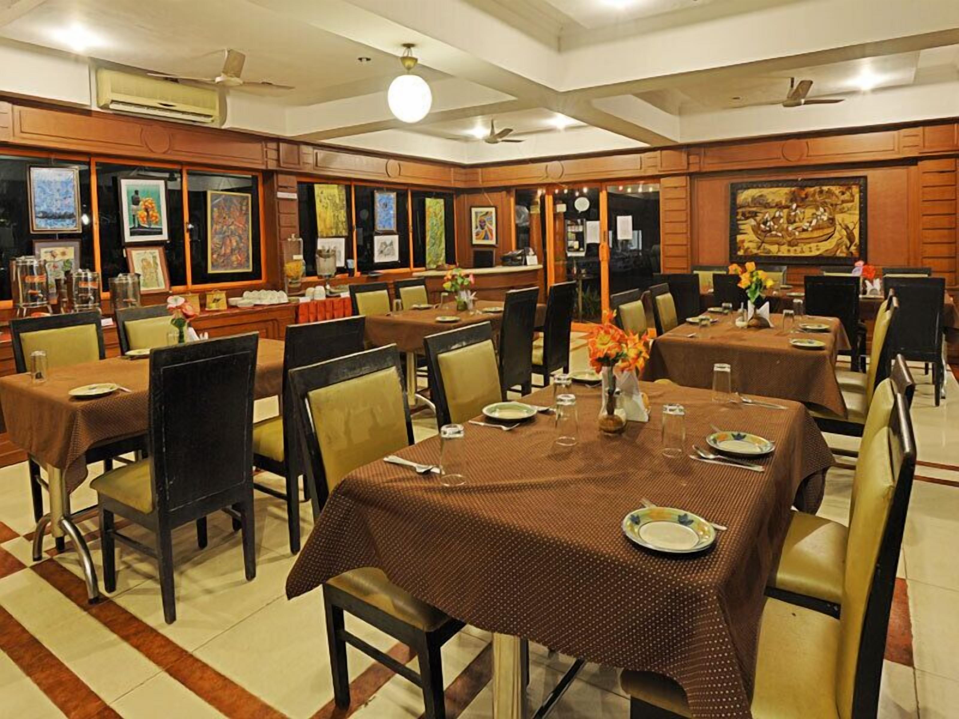 A dining area with multiple tables, chairs, and artwork on the walls.