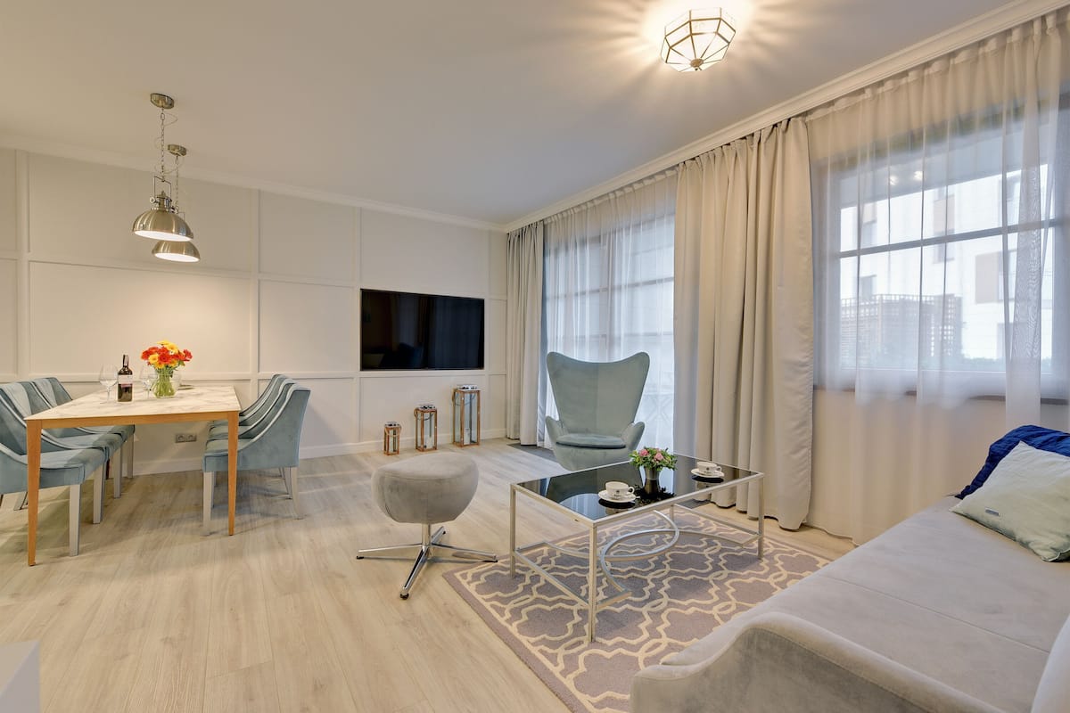 Un salon moderne comprenant un coin repas, un canapé, un téléviseur et une fenêtre avec des rideaux.
