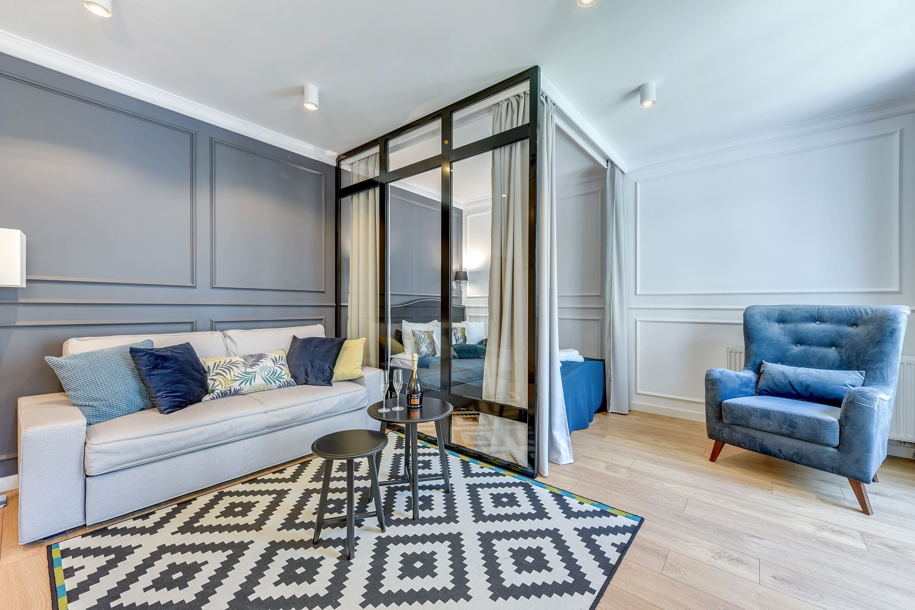 Una sala de estar moderna con un sofá, un sillón y un separador de vidrio.