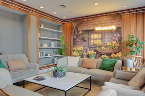 A modern living room with a sofa, armchairs, a coffee table, and a bookshelf. - GRANO APARTMENTS Gdańsk Motława SPA & Wellness (Gdansk)
