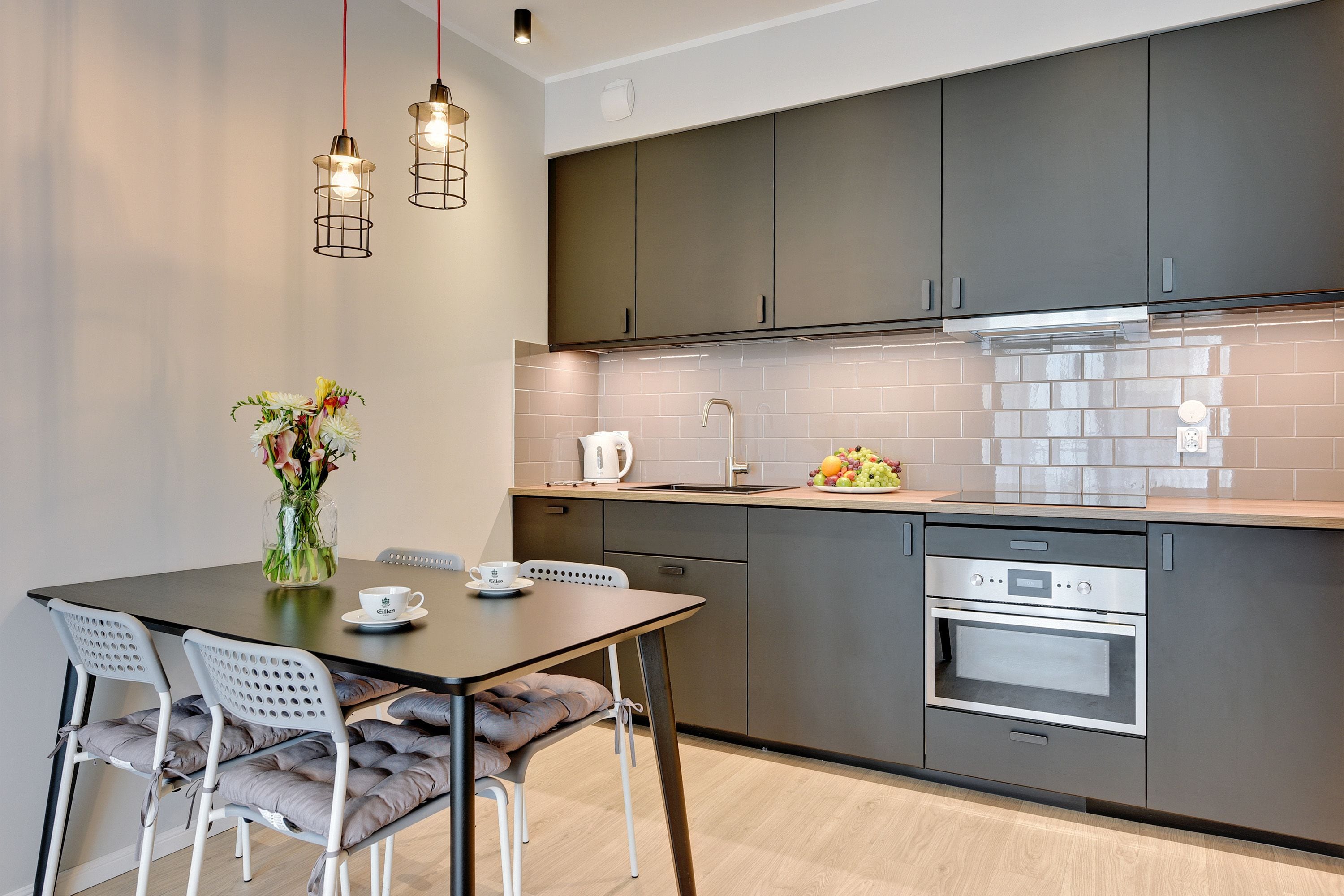 A modern kitchen with dark cabinets, a stainless steel oven, and a tiled backsplash.