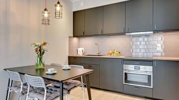 A modern kitchen with dark cabinets, a stainless steel oven, and a tiled backsplash.