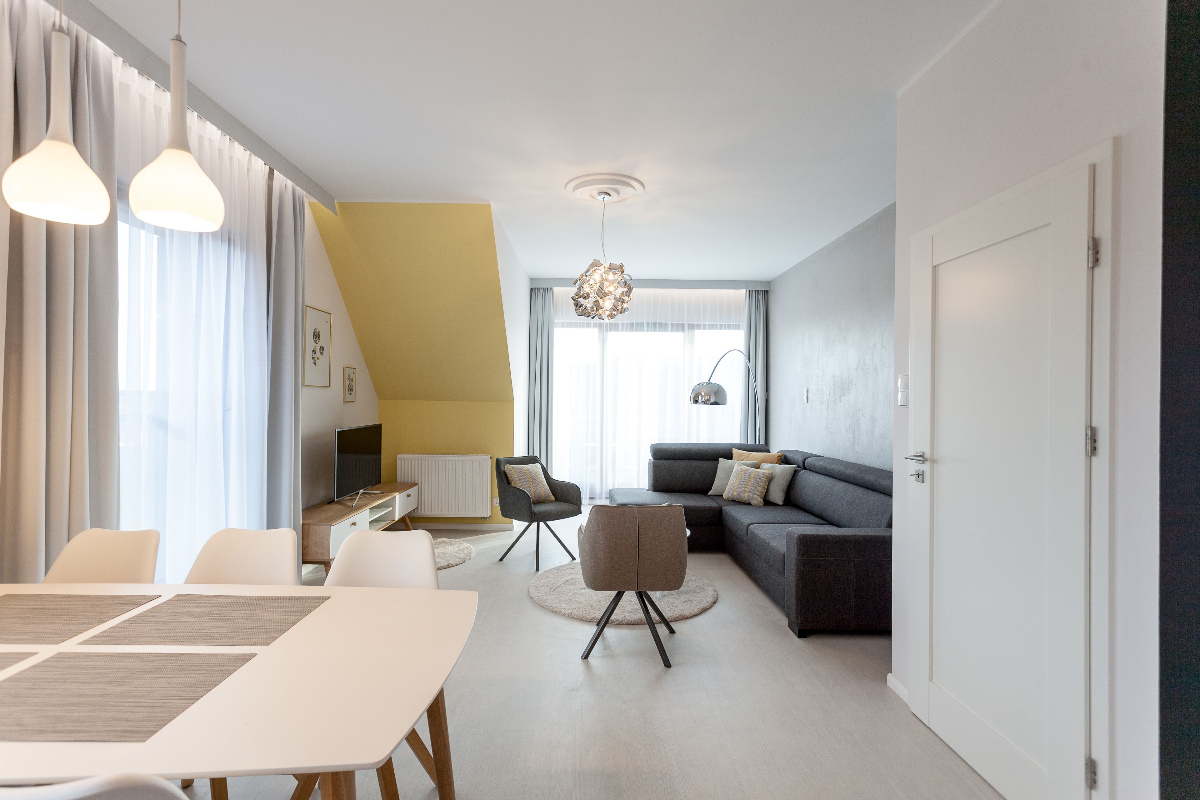 A modern living room with a dining area, a sofa, and a TV.