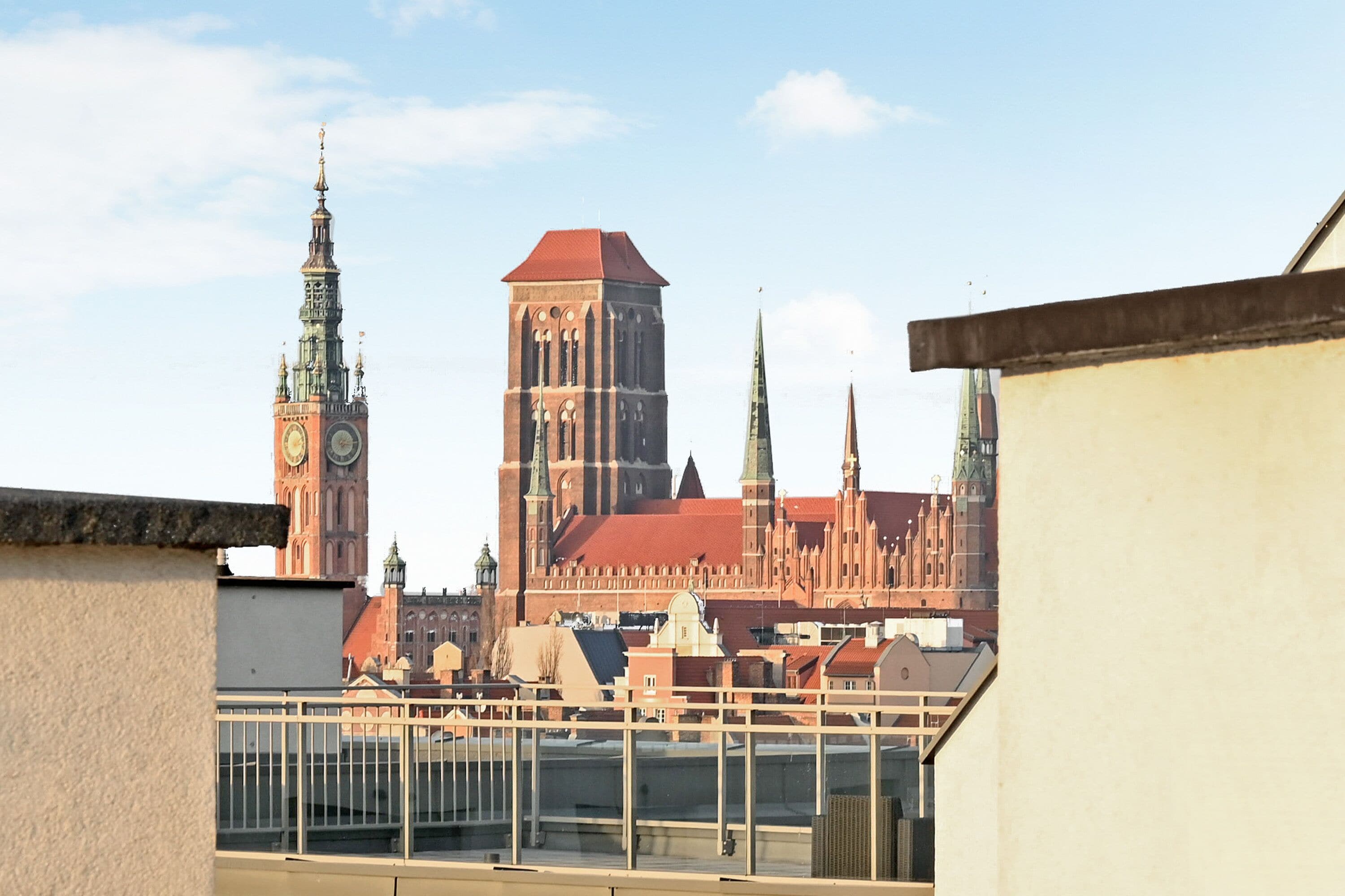 A view of a historic building with a prominent clock tower and spires, viewed from a balcony.