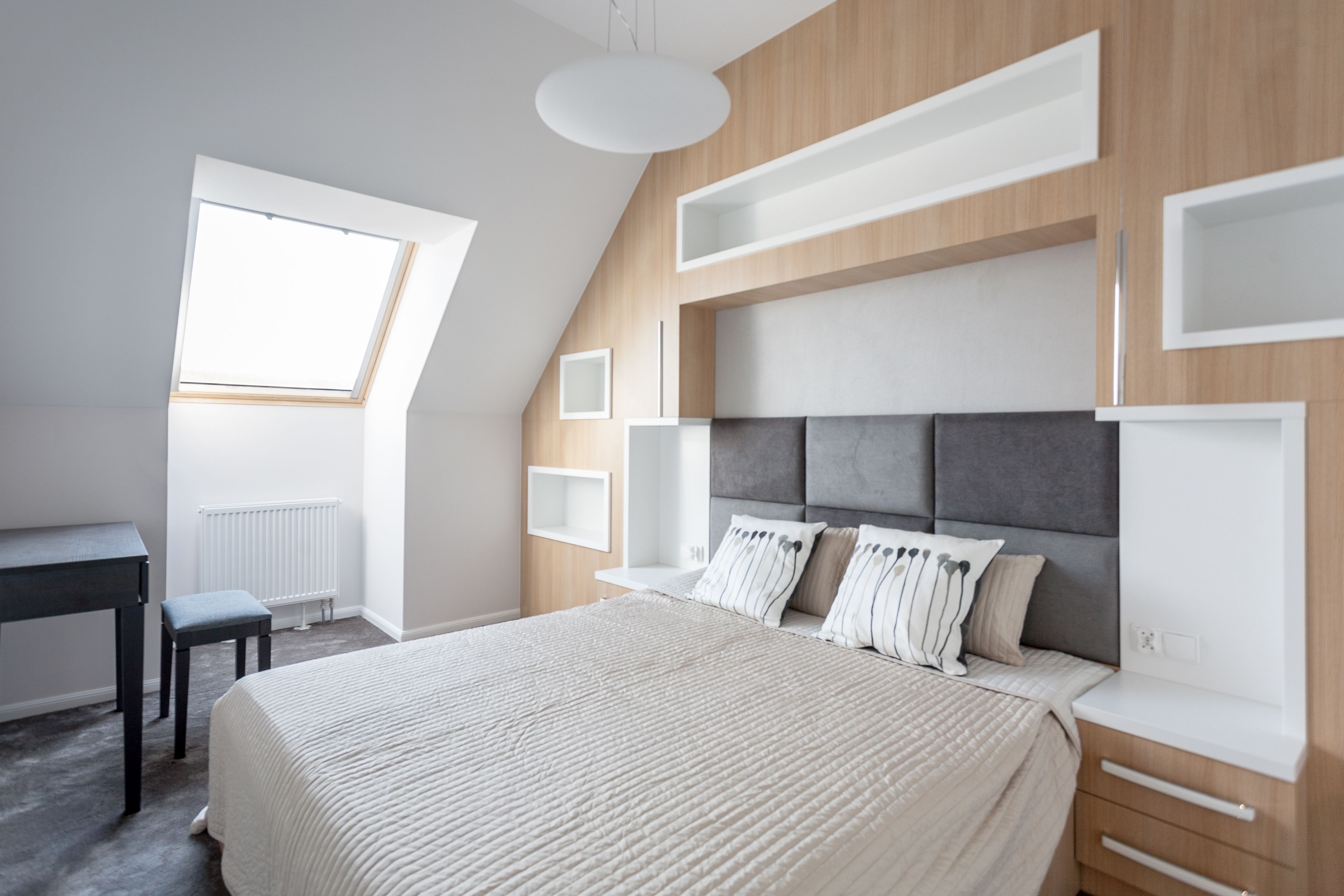 Quarto com cama grande, escrivaninha e claraboia.