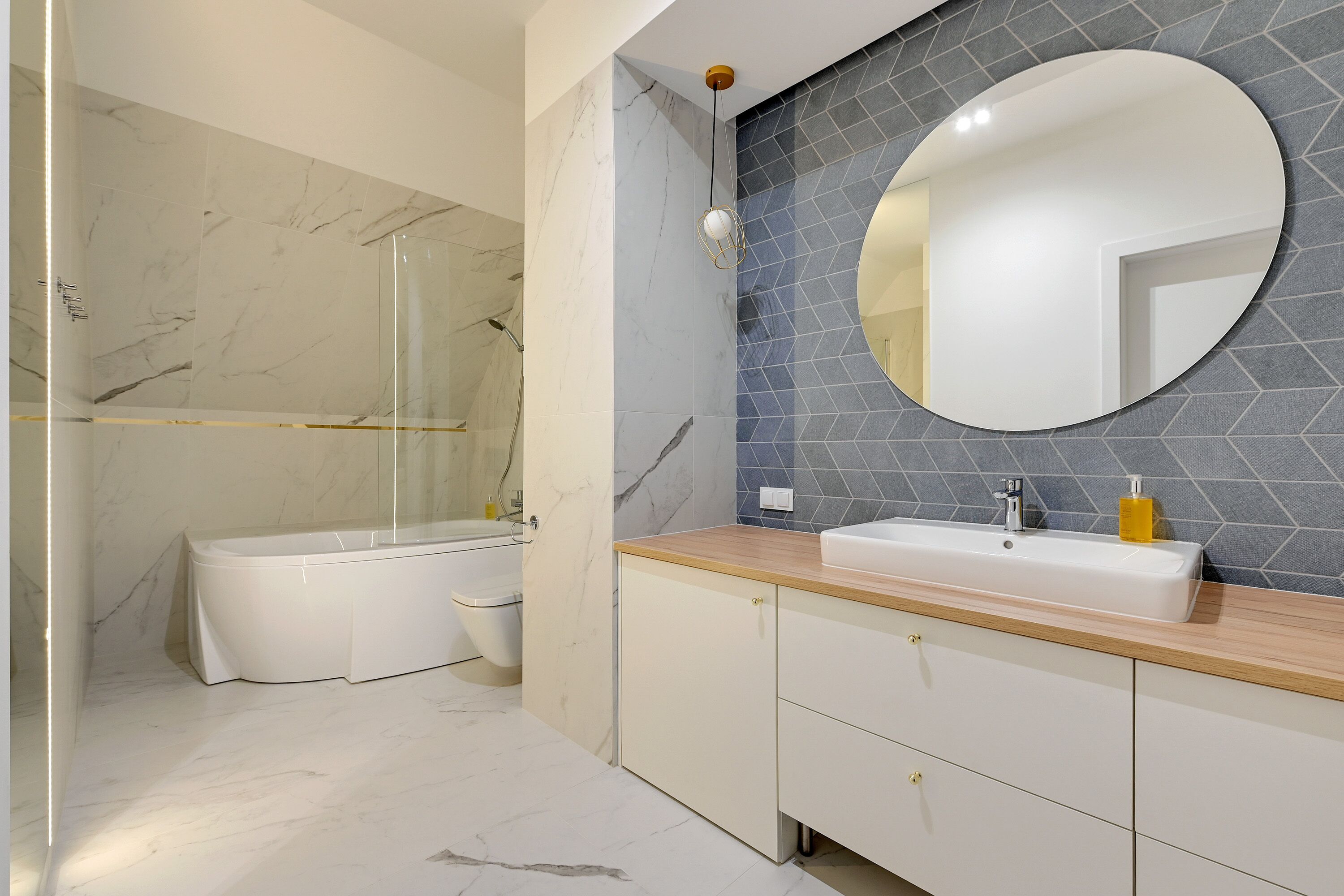 A modern bathroom with a marble floor, a bathtub, a sink with a mirror, and a shower area.