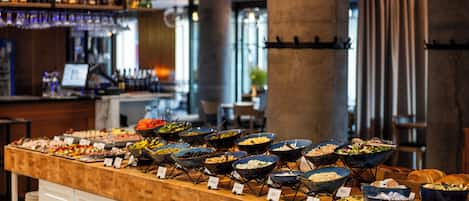 A buffet with various food items and a bar area in the background.