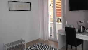 A room with a desk, chair, air conditioning unit, and a TV.