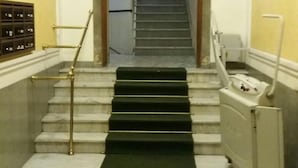 A staircase with a black carpet leading up to a landing.
